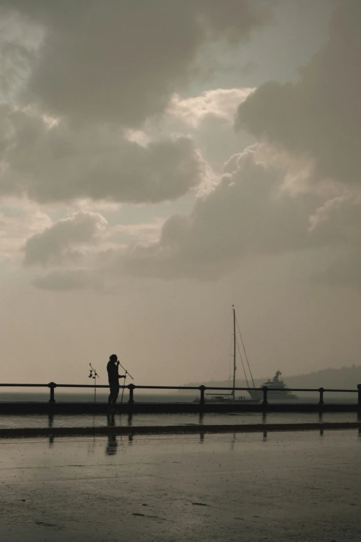 a couple standing on the edge of the dock by the ocean