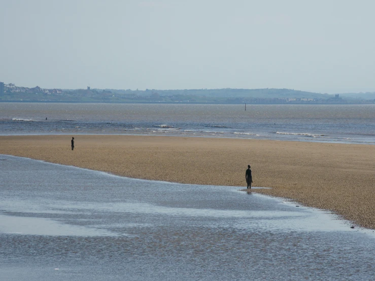 people walking along the beach near a large body of water