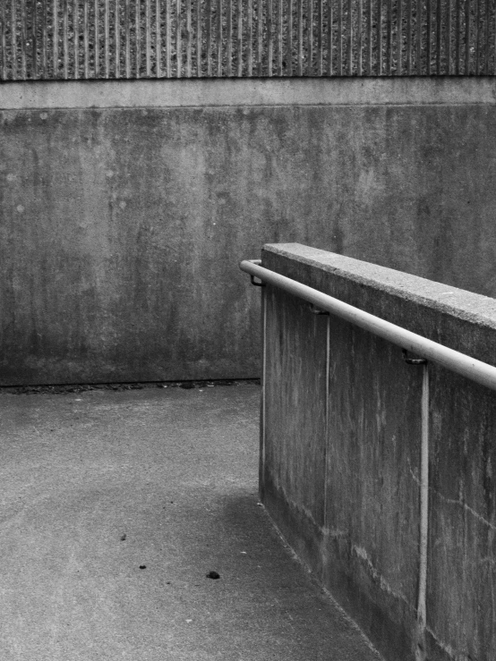 a bench sitting on the side of a street next to a wall