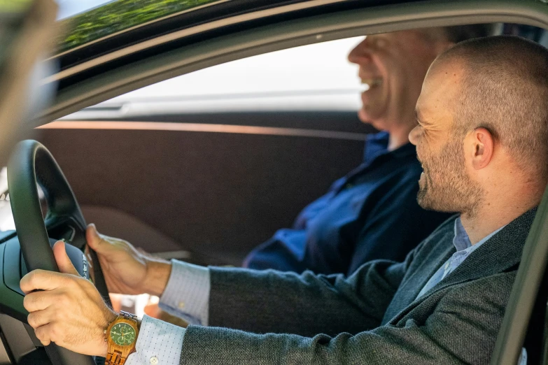 two men driving together while the man is wearing a suit