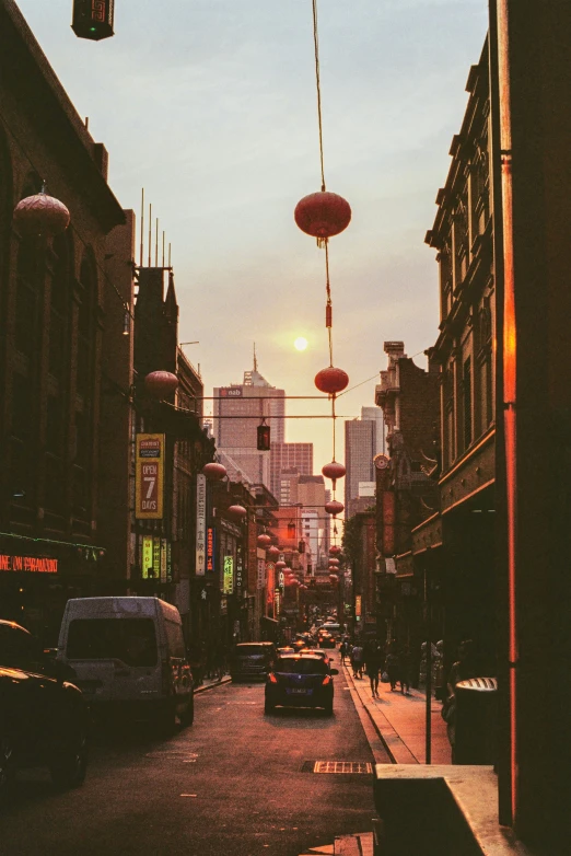 a view down an alley with traffic passing and lights above