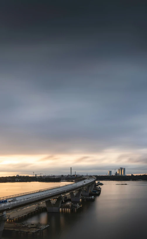 a city skyline over the water with some boats at sunset