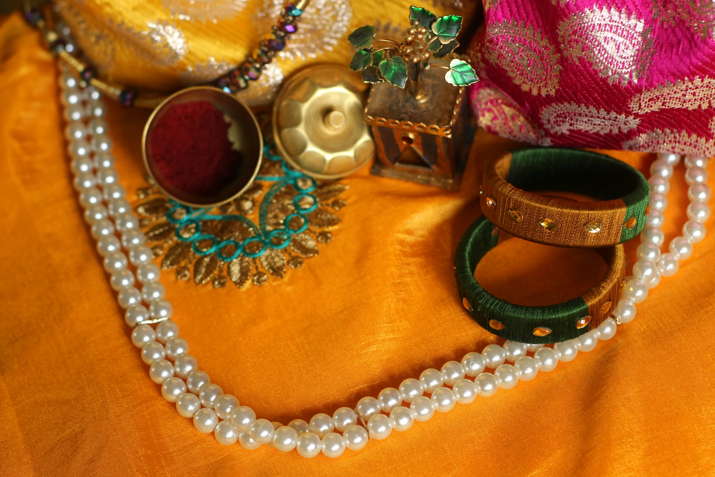 several necklaces and accessories laid out on an orange cloth