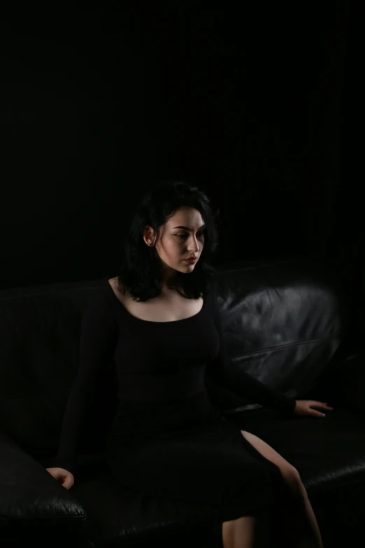 a woman in black sitting on a couch