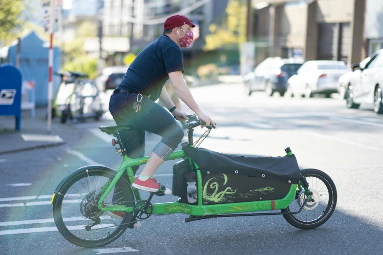 a man in black shirt riding on bike with a green bike with bag strapped to the handlebars