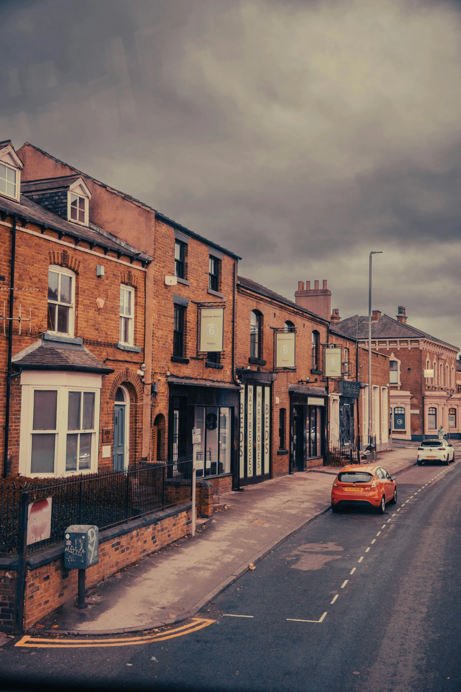 a red car is parked next to some brick buildings