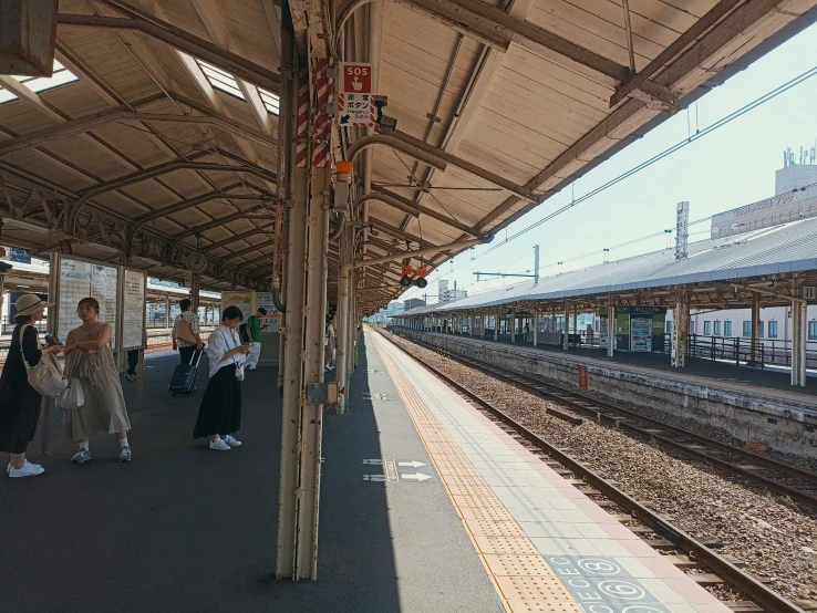 several people waiting at a train station for the next passenger