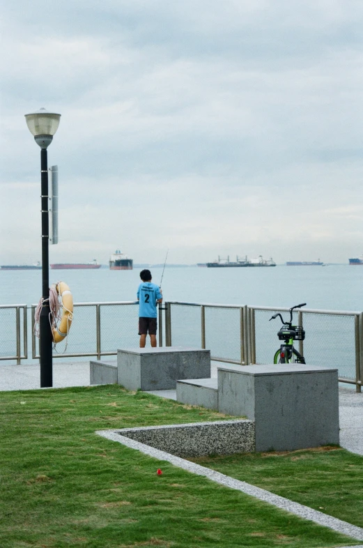 a person on the grass looks at the water