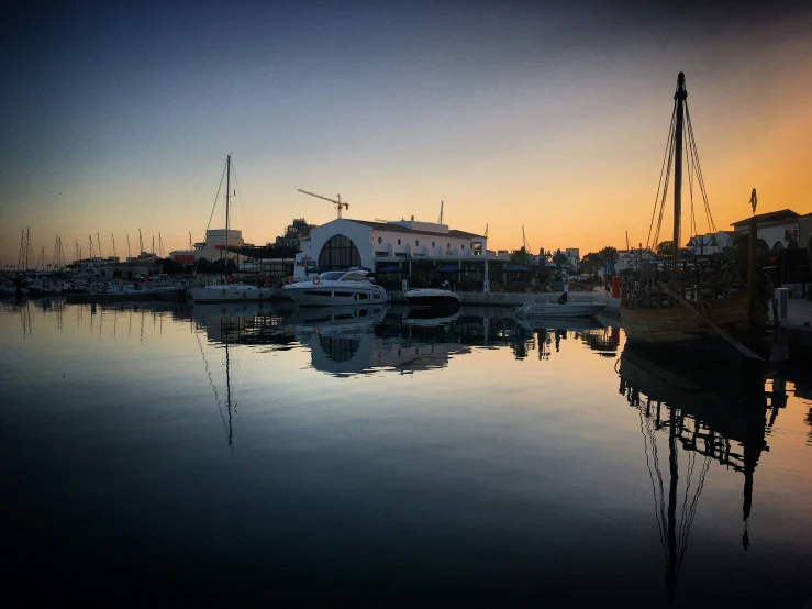 the sun is setting behind the boathouse and it reflects in the water