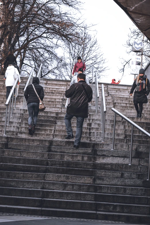 four people with umbrellas are going up some steps