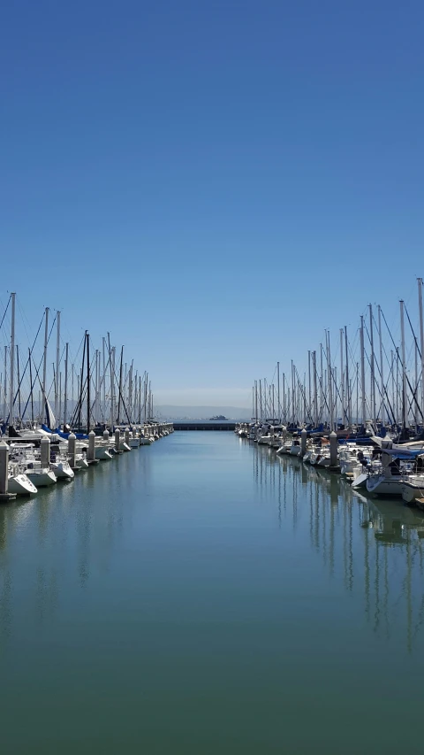 many boats docked in the water under a blue sky