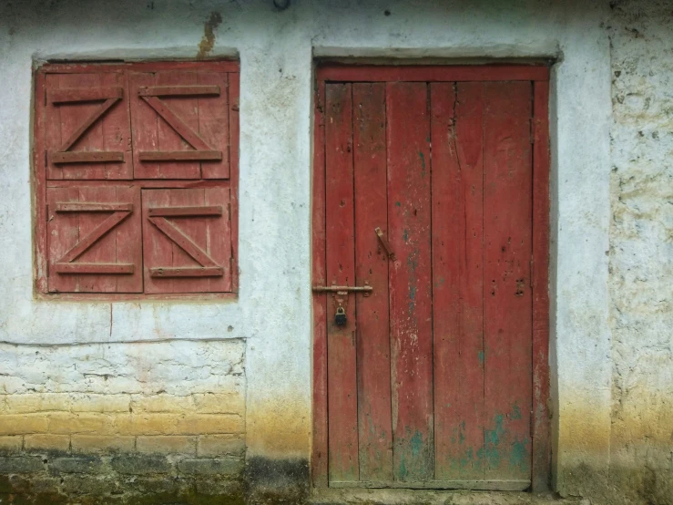 an old building with two red doors and window frames