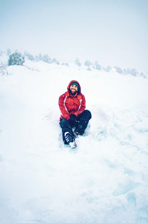 the person sits in the snow on top of a hill