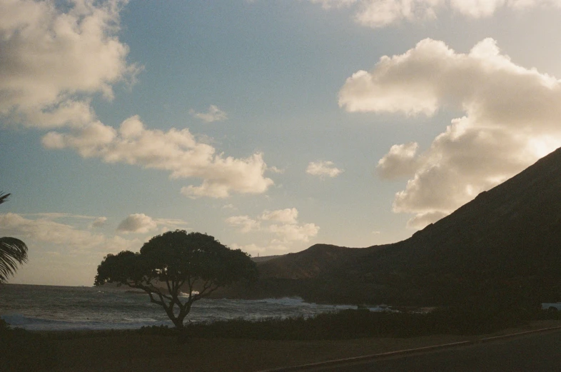 the sun setting on a mountain near a beach