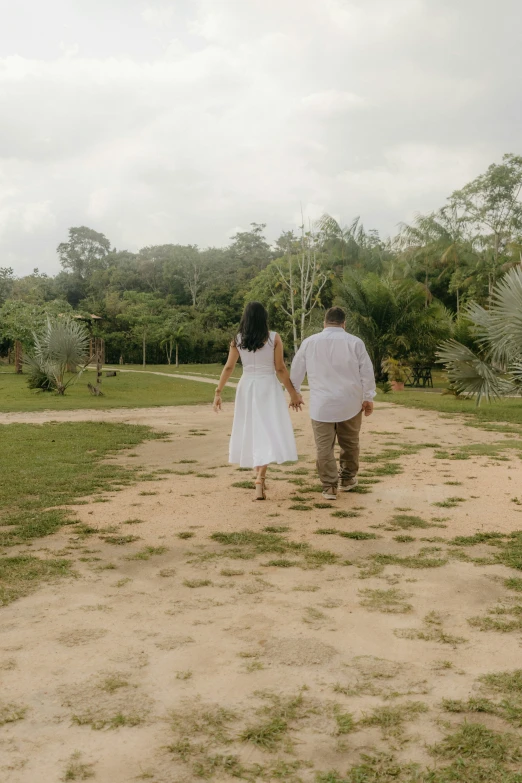 a young man and woman are walking on the dirt