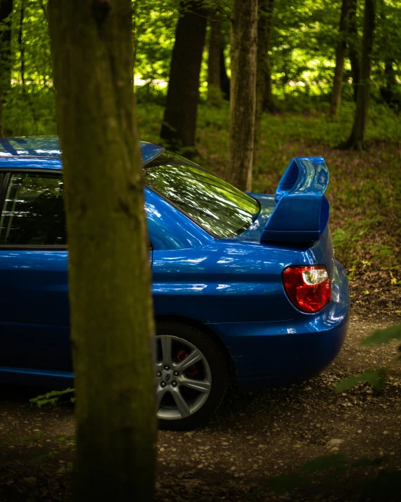 a blue car is in the woods with its hood open
