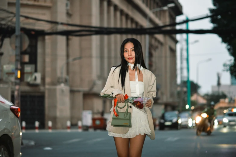 woman in white dress carrying her purse standing on street corner