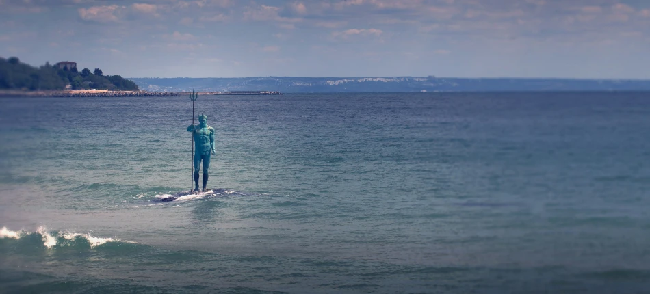 a person in the ocean standing on a surfboard with an umbrella