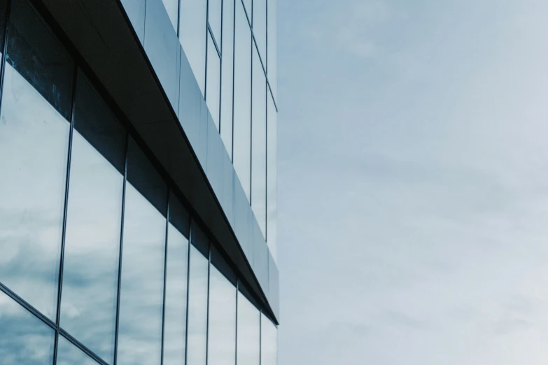 the side of a skyscr reflecting blue skies