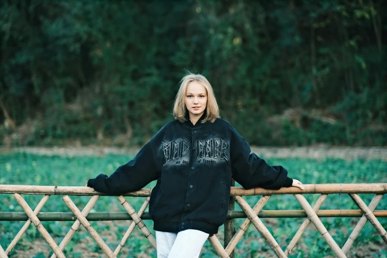 a woman wearing a black sweatshirt posing against a fence