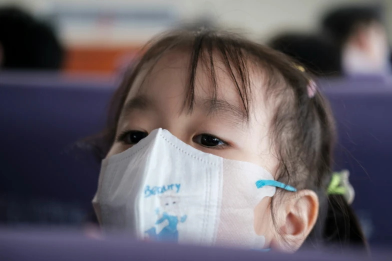 a young child in a protective mask sits in an airplane