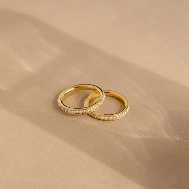 two gold wedding bands on a tan background