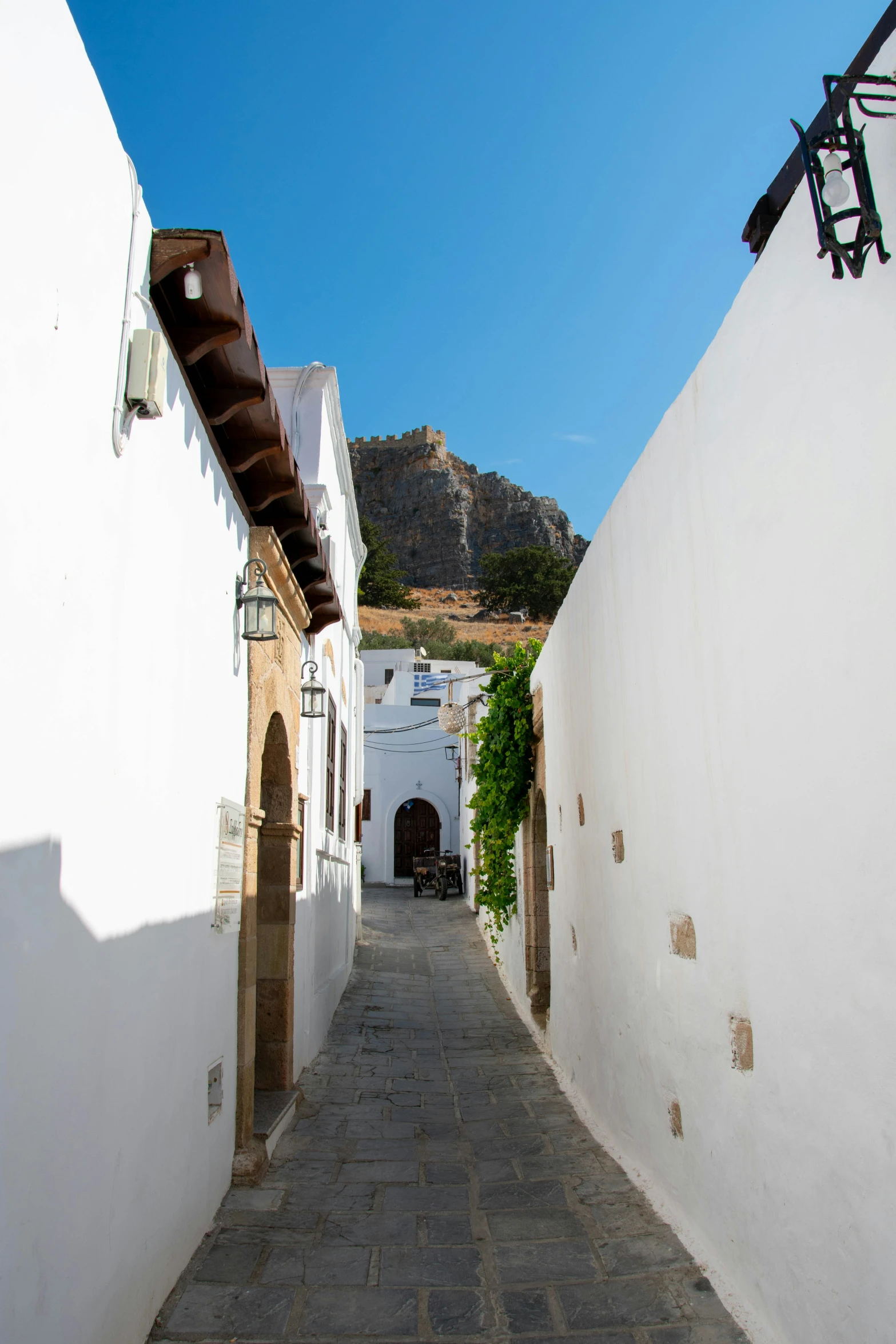 a cobbled path leads to an arch with a mountain in the background