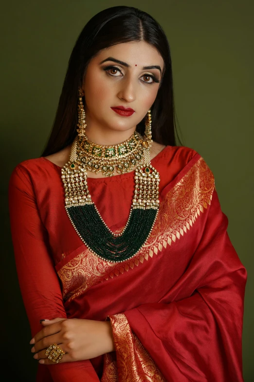 a beautiful woman wearing a red saree and green jewelry