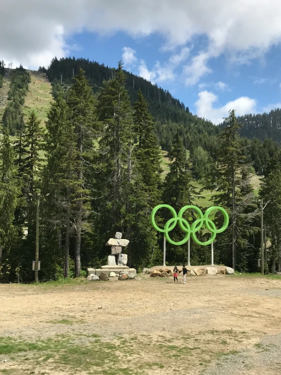 two people in front of a sculpture with the olympic rings painted on it