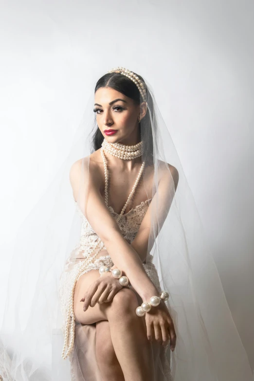 a beautiful young lady wearing a white dress sitting on a stool