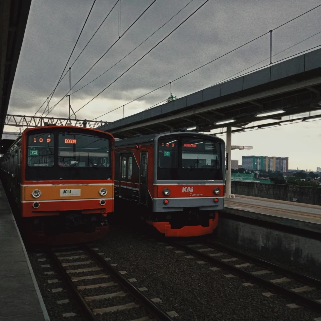two trains sitting on the tracks in a station