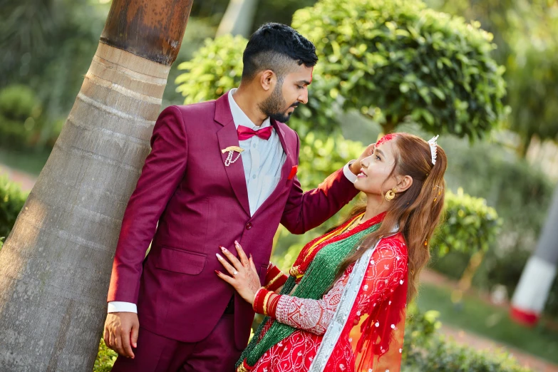 the bride and groom pose in a red and green wedding suite