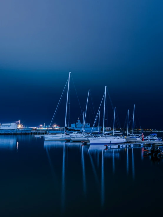 several boats in a body of water with city lights behind them