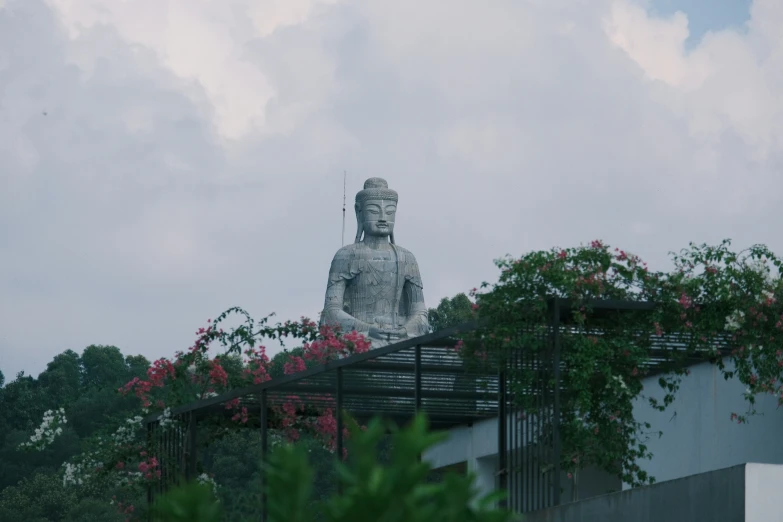 a gray and white buddha statue surrounded by red flowers