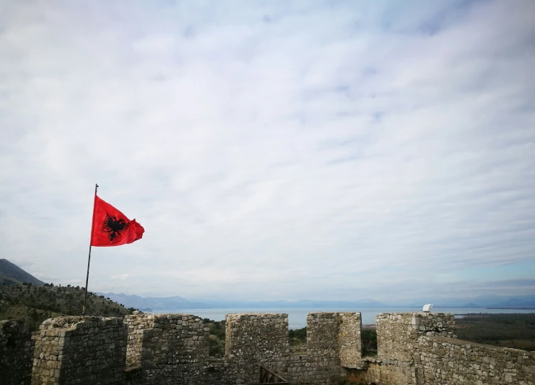 a large red flag hanging from a stone wall