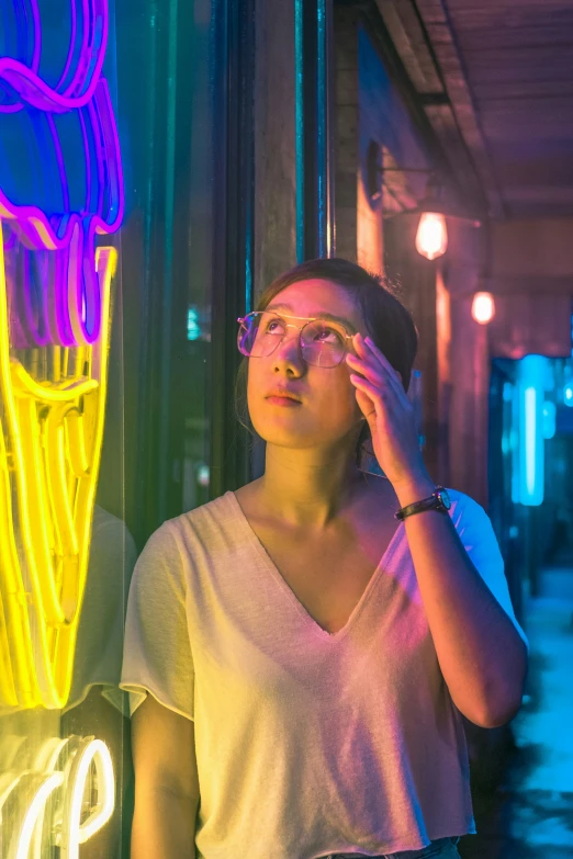 a woman in glasses standing next to neon lights