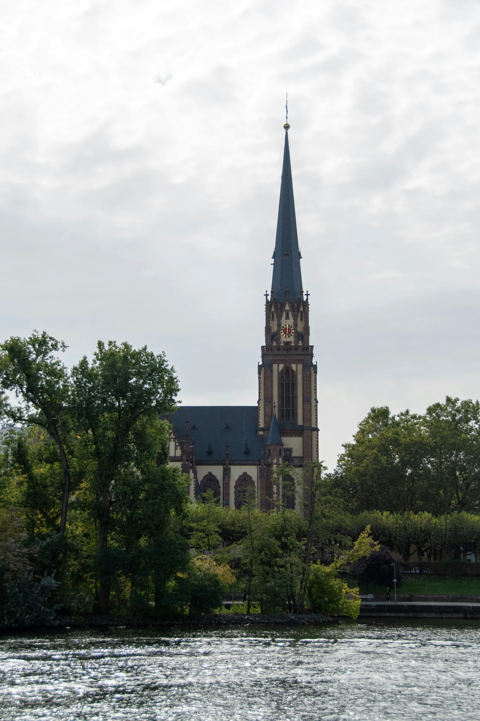 an old cathedral sits on top of the tree - lined banks of a river