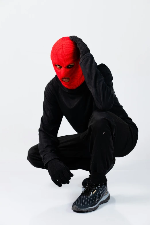 man dressed in red and black on skateboard and wearing an over sized, ski - wear mask