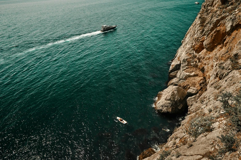 a boat driving through the ocean near cliffs