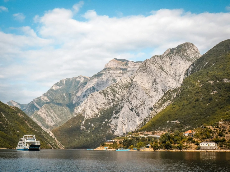 a cruise ship sails on a river between mountains