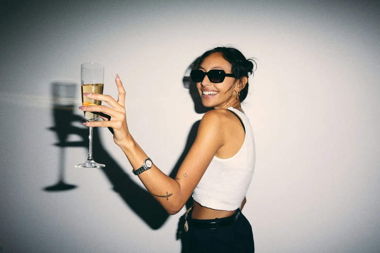 a woman with sunglasses holding up a glass