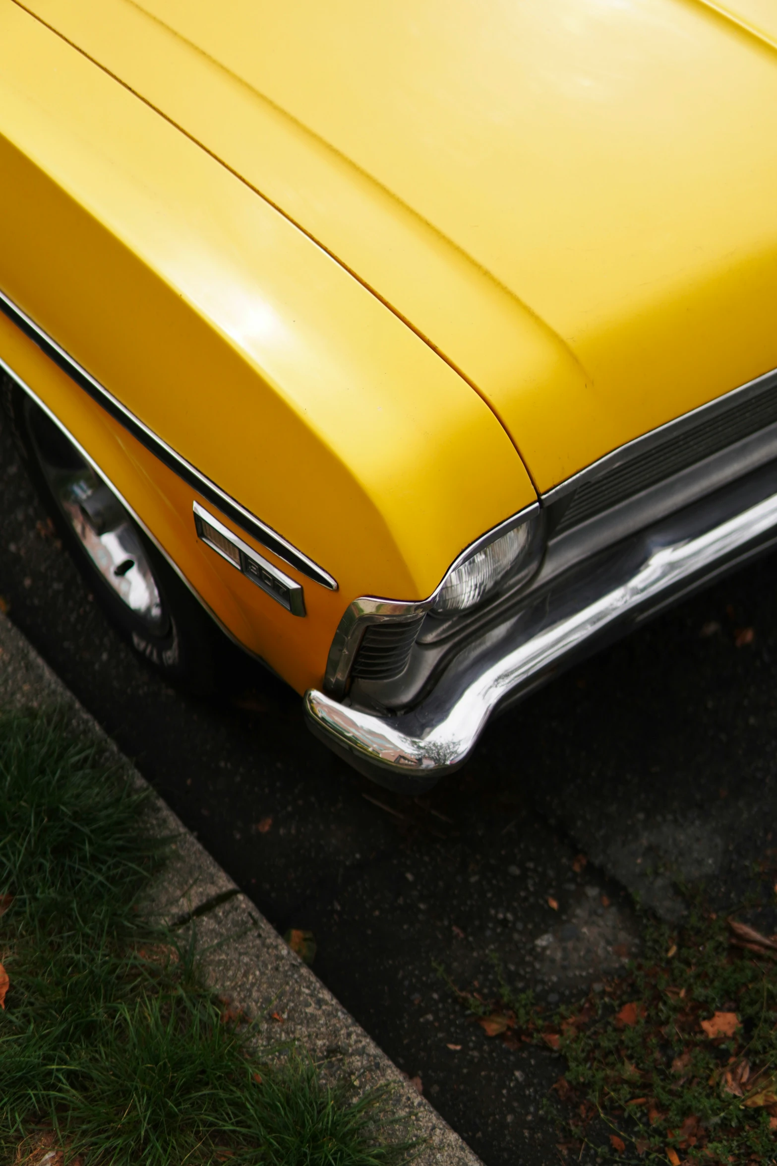 an old yellow car is parked on the side of the road