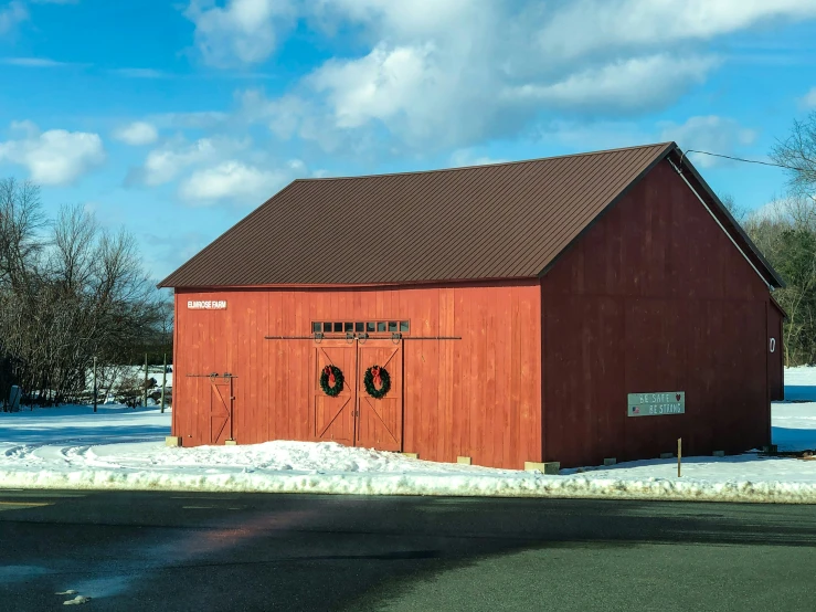an empty red barn with two round windows and snow on the ground