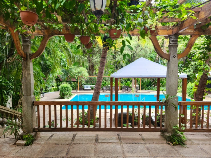 a wooden deck sitting next to a large pool surrounded by greenery