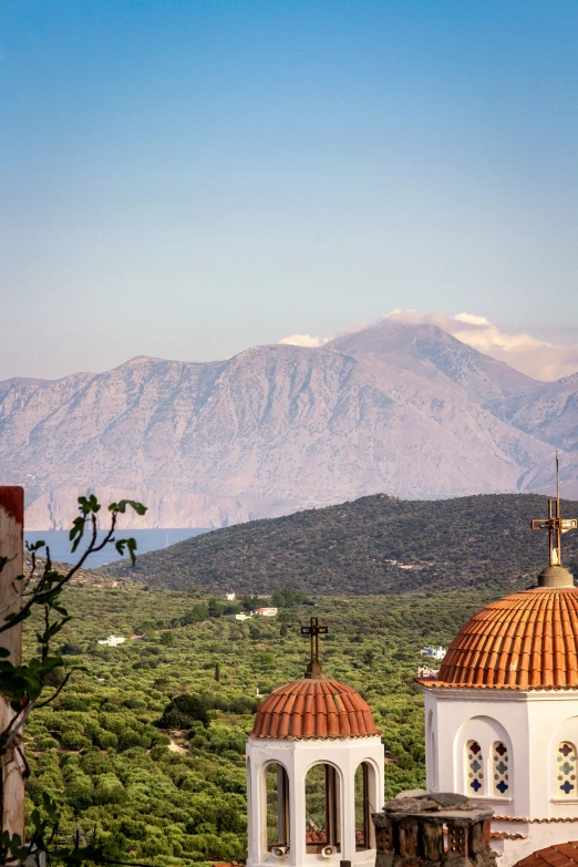 a bell tower sitting over a field of grass and mountains