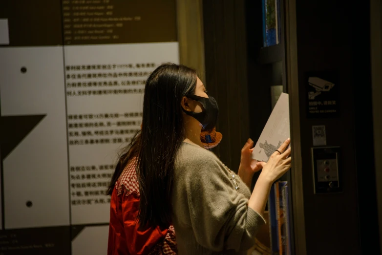 a woman holding up a paper next to a black device