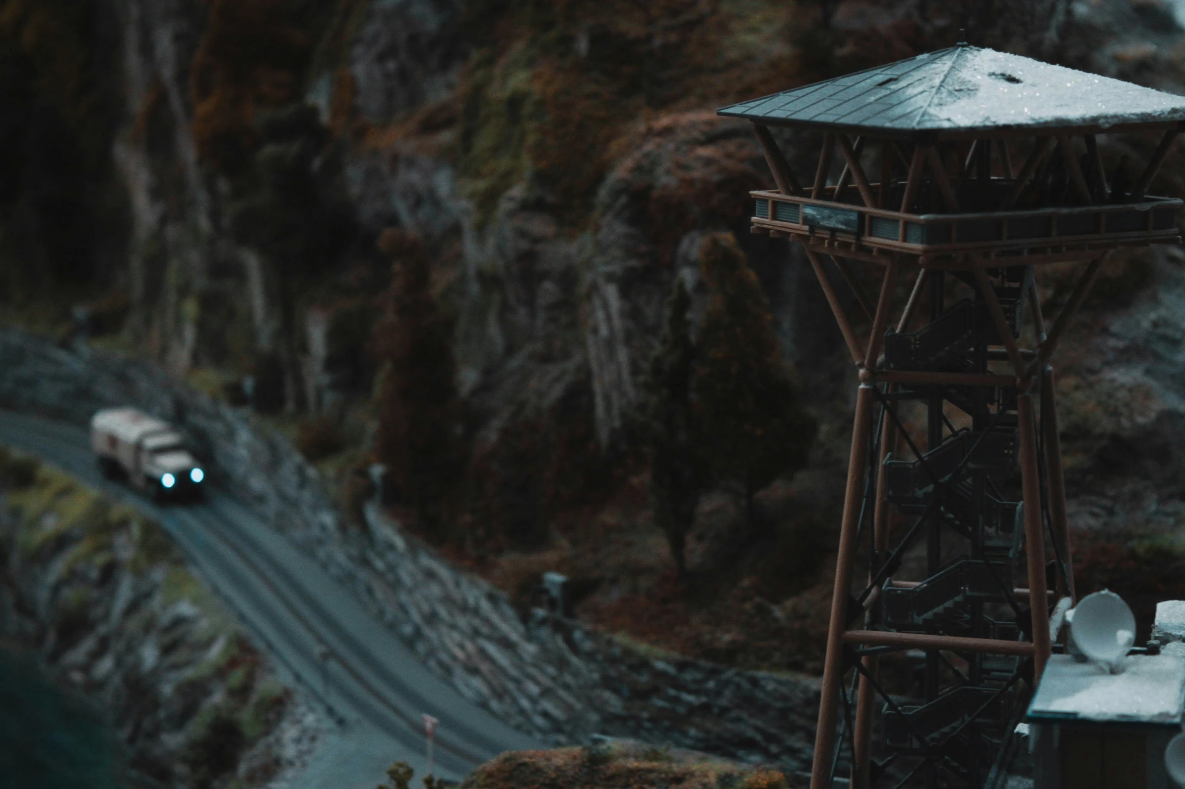 a toy train set, on a mountain tracks, with a white car going down the track