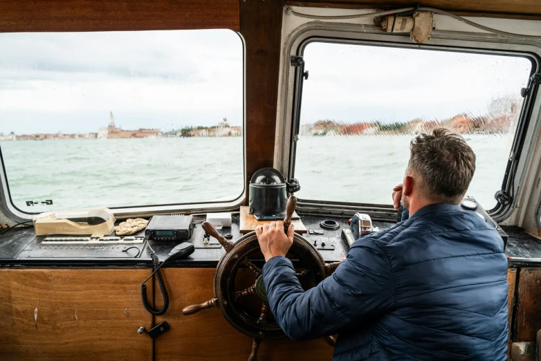 the man is driving the boat while holding the steering wheel