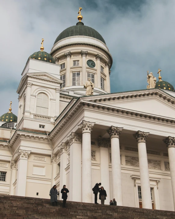 several people are standing outside of an ornate white building