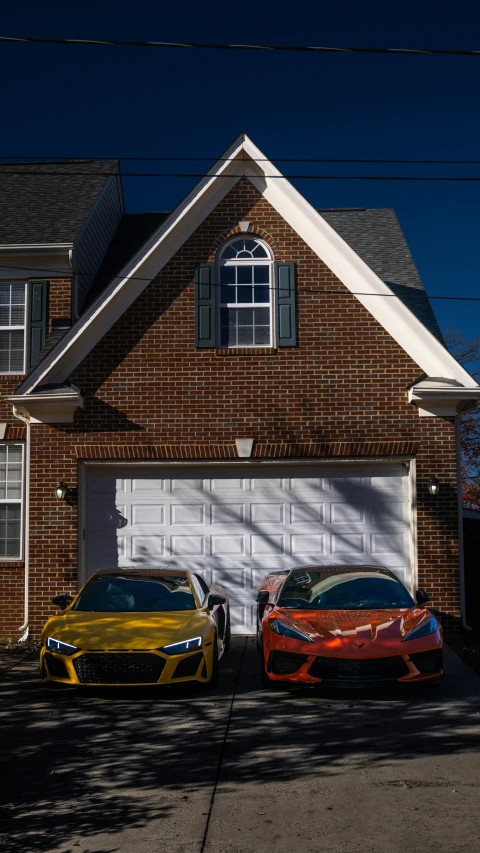 two sports cars parked in front of a house